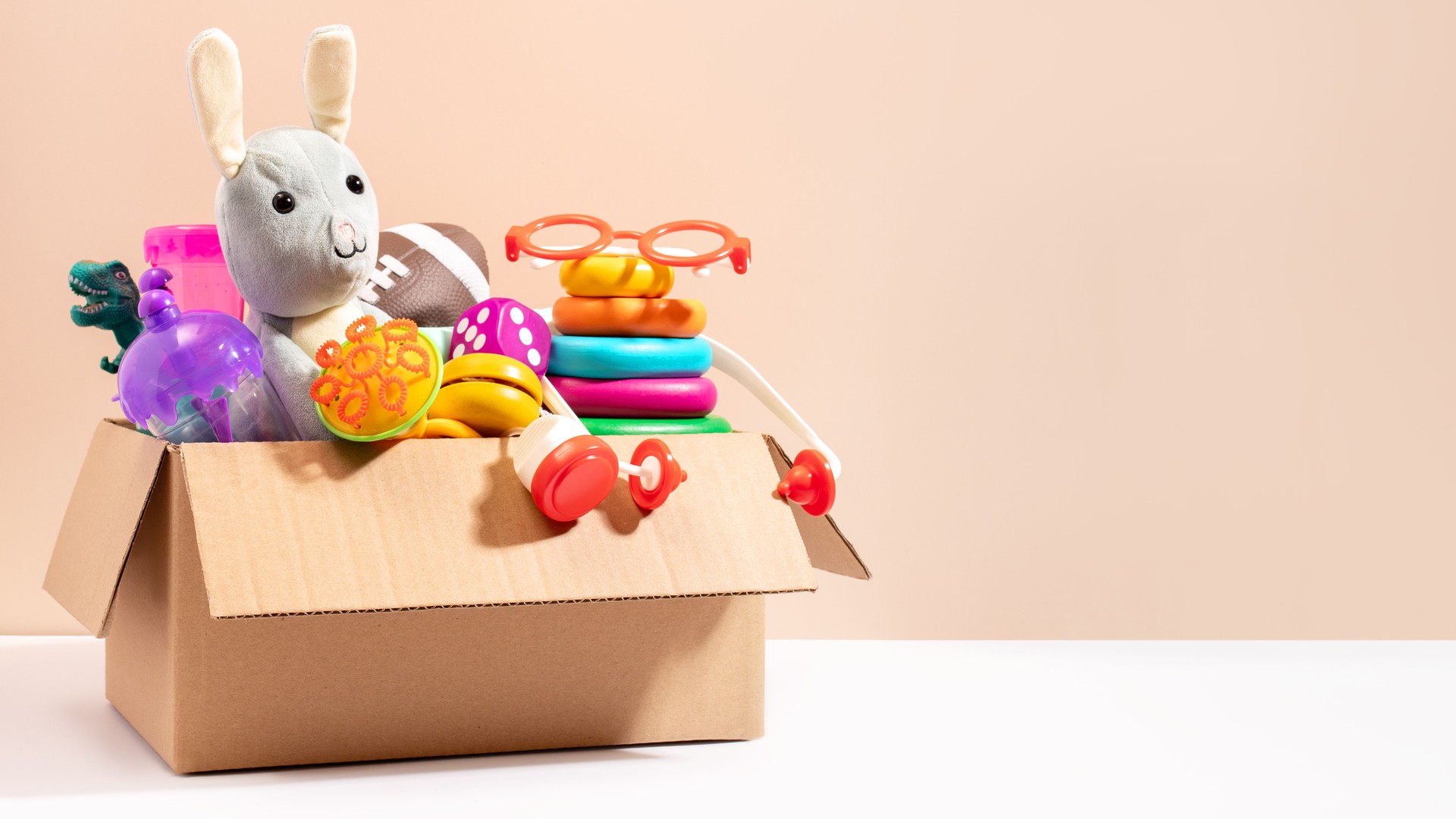Toys for children in a box ready for donation on beige, copy space. Concept of toys donations, charity for children