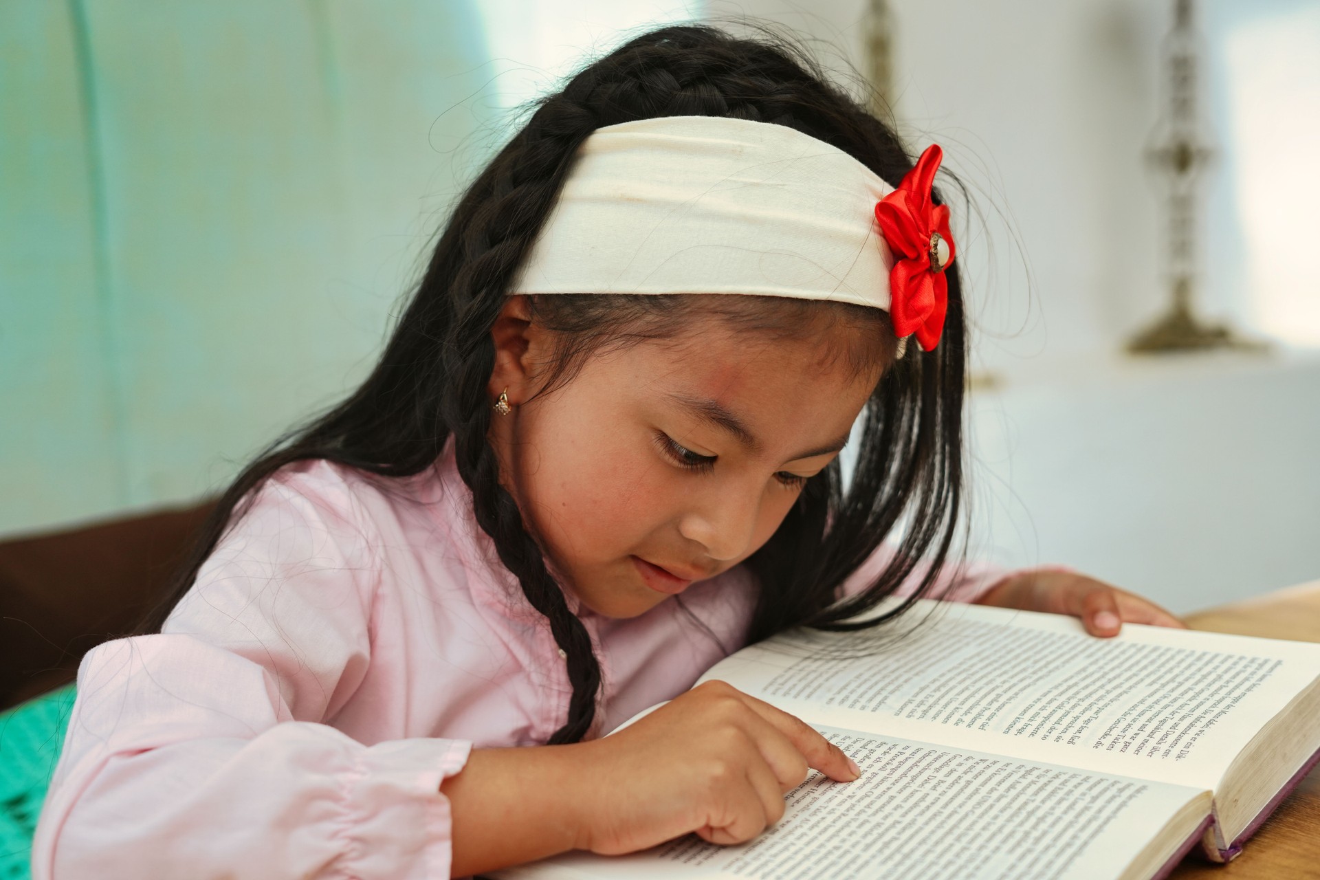 Elementary age girl reading a book and pointing at words