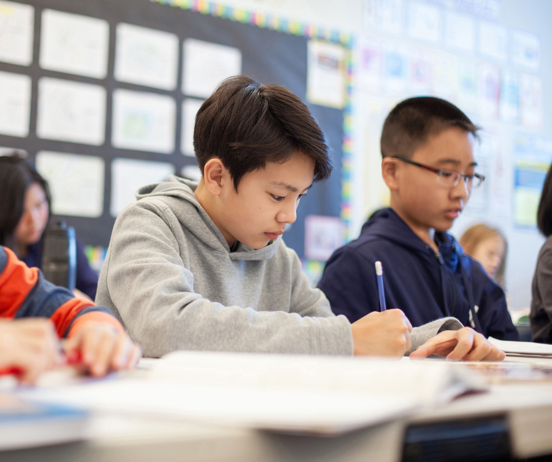 Asian multiracial Korean Japanese boy studies in elementary school classroom with classmates