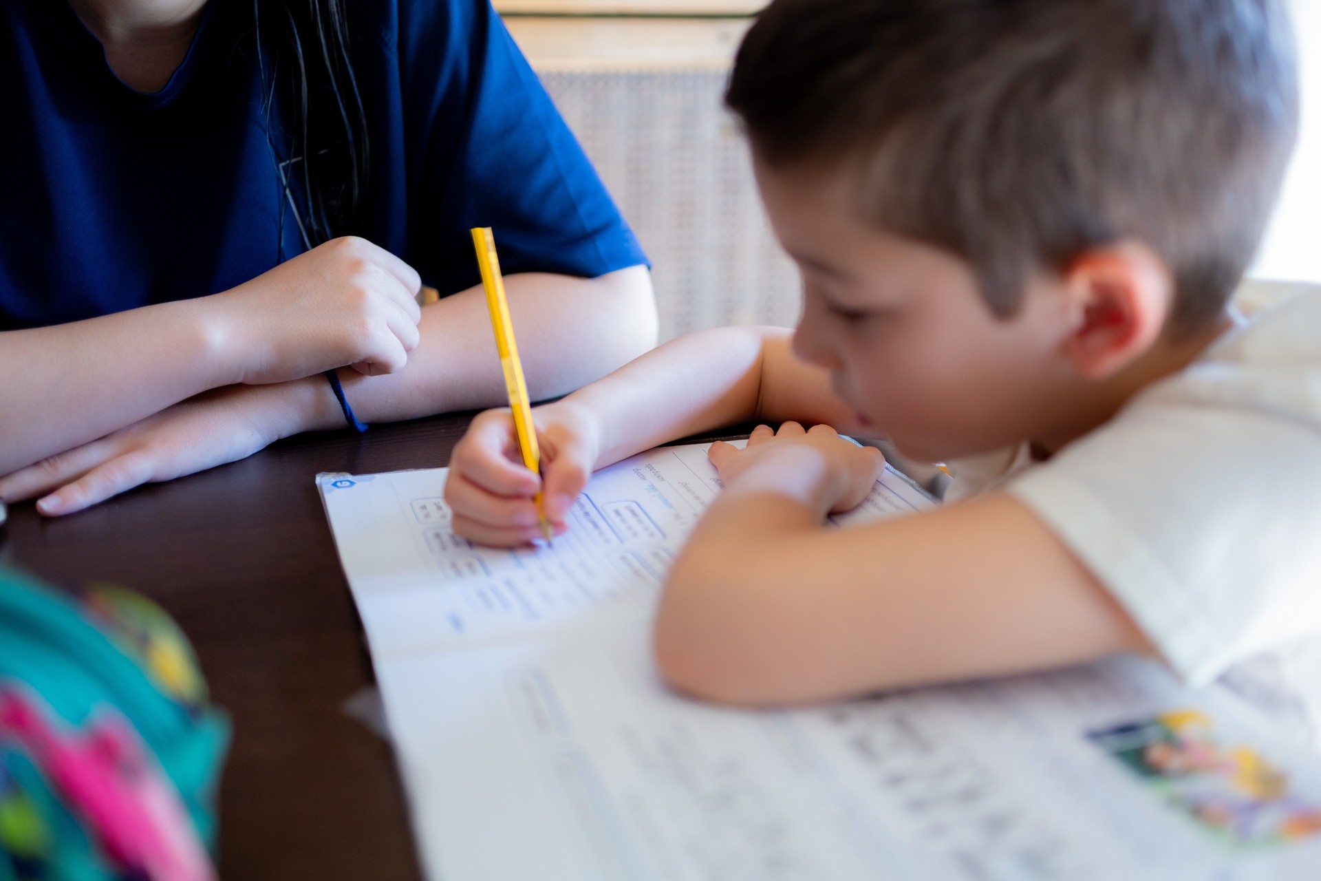 Young boy doing homework with tutor's support at home